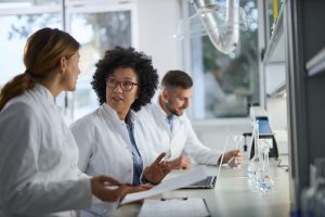 Medical experts talking while working on medical research in laboratory, engaging in the peer review process.